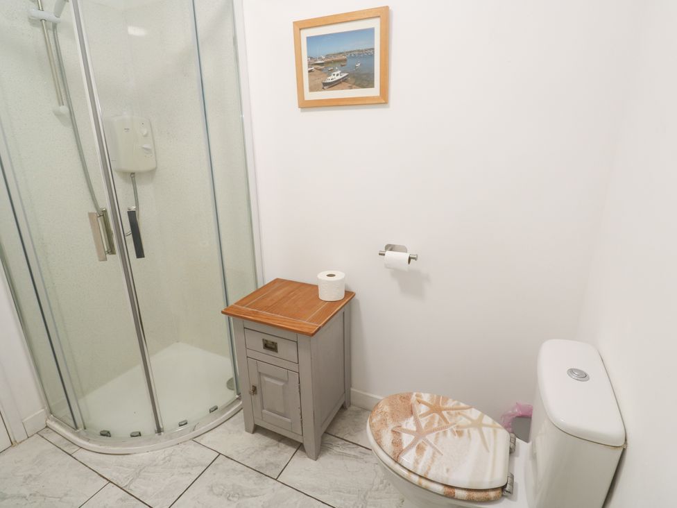 A bathroom with a shower, toilet, and small cabinet at Sandyfeet near Roskear Croft Camborne