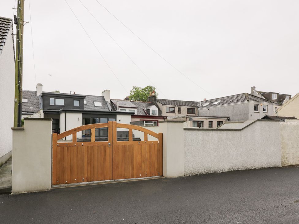 A gate and wall with houses in the background at Beach House Stranraer