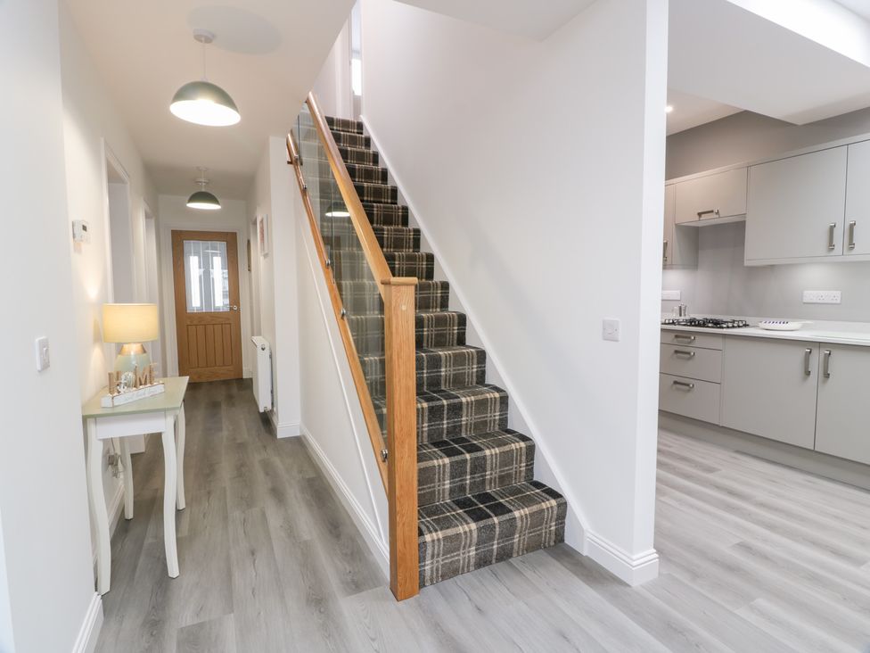 A hallway with a staircase and lamp at Beach House in Stranraer