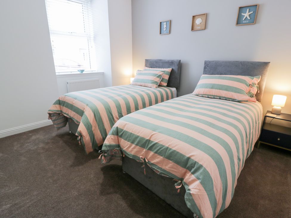 A bedroom with two beds and a nightstand at Beach House in Stranraer