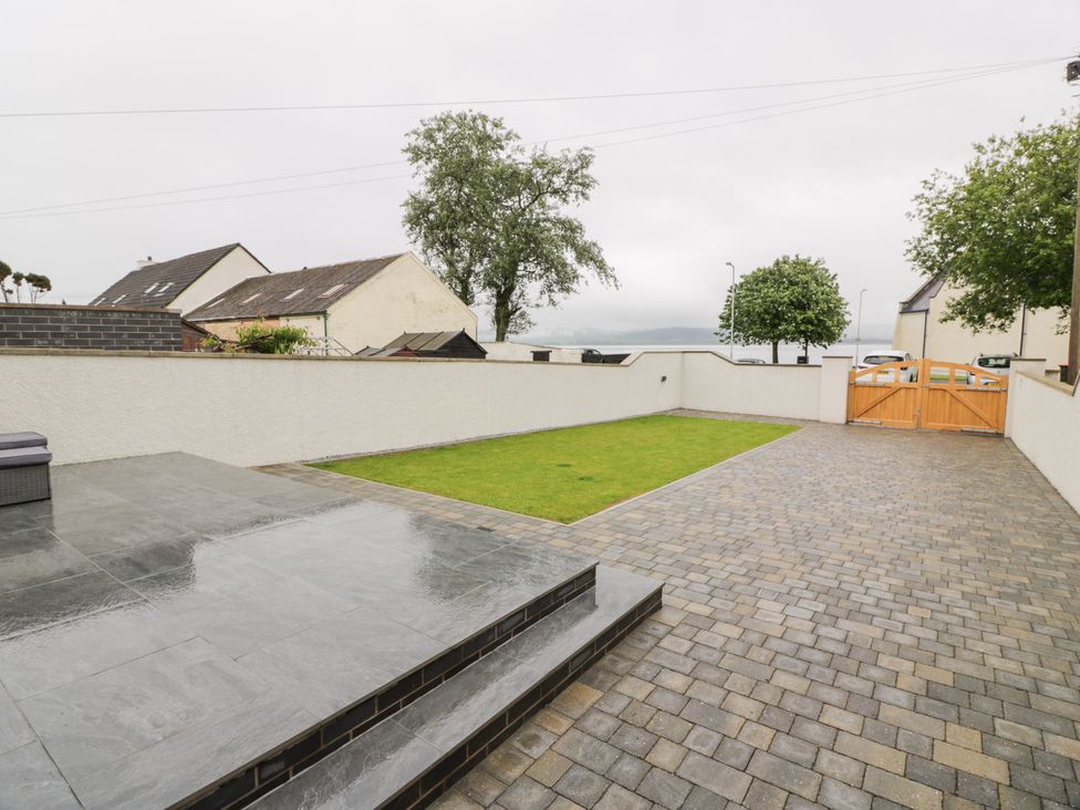 A garden with a paved area and grass at Beach House in Stranraer