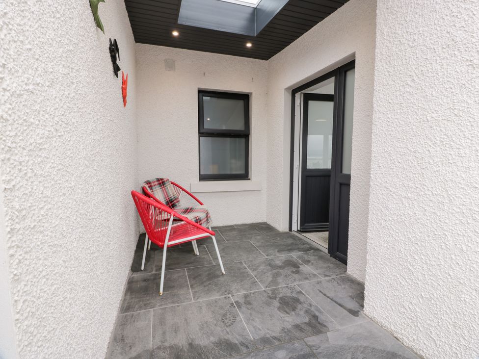 A porch with a red chair and window at Beach House in Stranraer