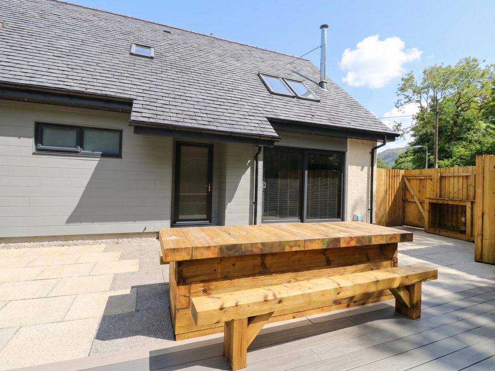 An outdoor area with a wooden table and house at Nevis Bridge House Fort William