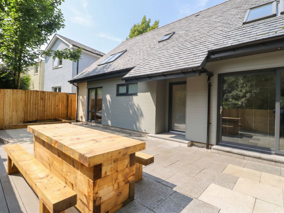 An outdoor seating area with a wooden table and benches at Nevis Bridge House in Fort William