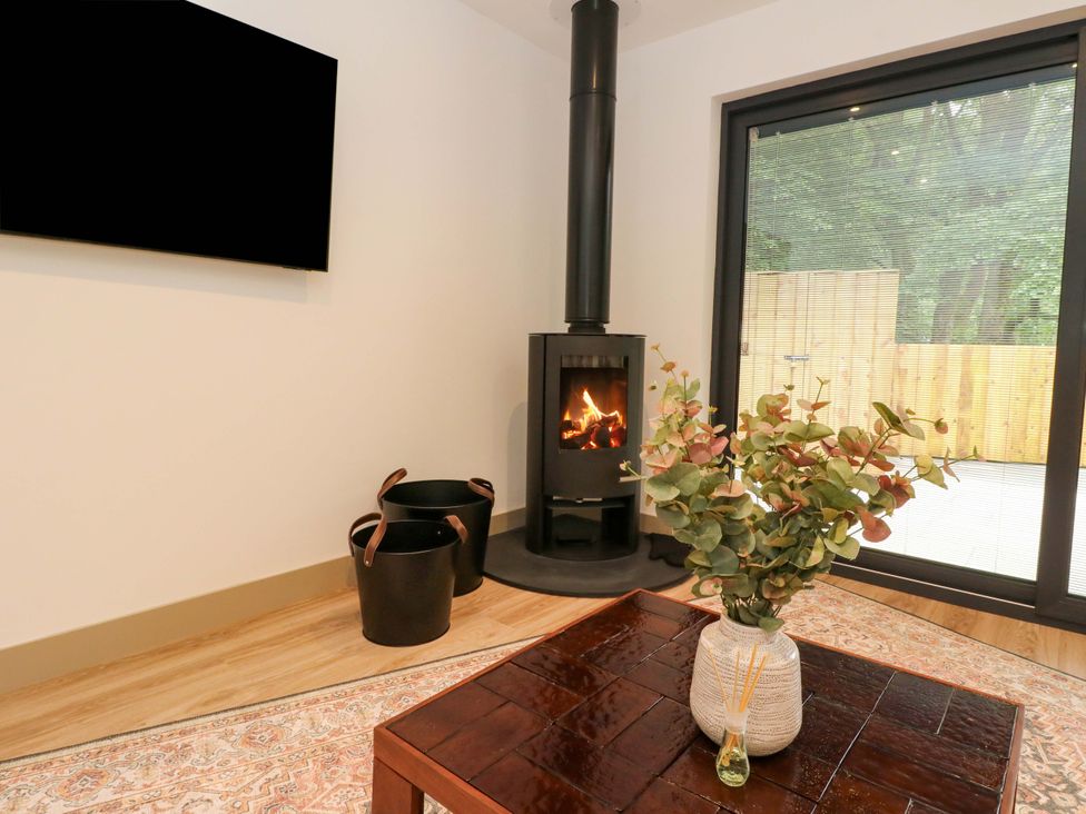 A living room featuring a wood stove and a table with a vase at Nevis Bridge House in Fort William
