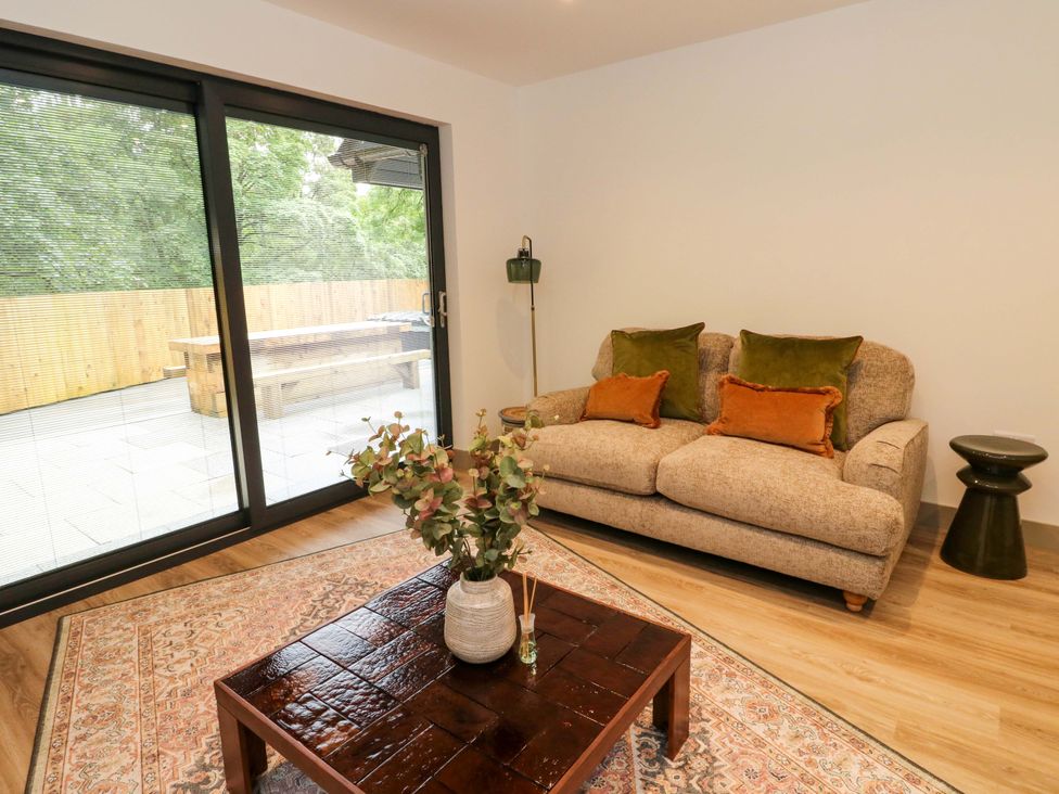 A living room with a sofa, table, and plant at Nevis Bridge House in Fort William