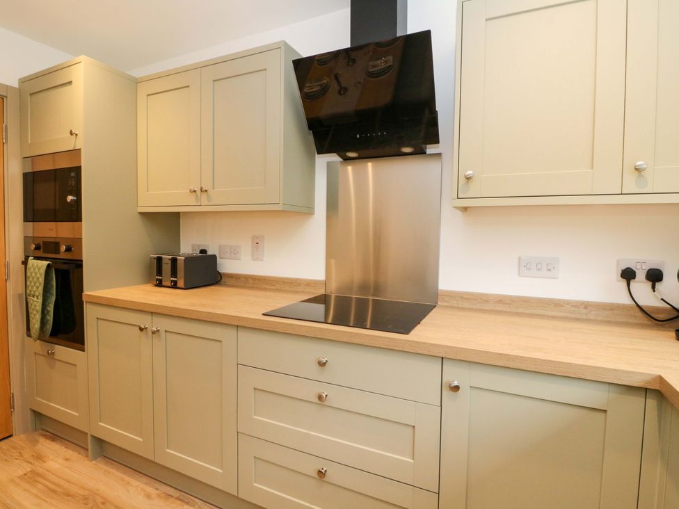 A kitchen with cabinets, oven, toaster, and cooker hood at Nevis Bridge House in Fort William