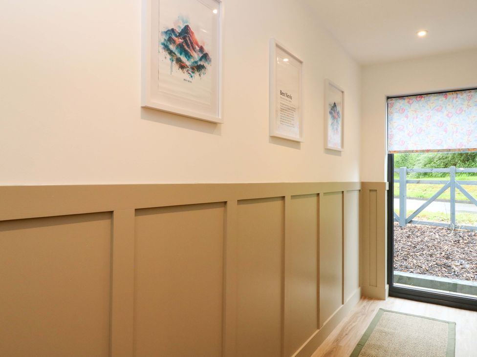 A hallway with wall art and a door leading outside at Nevis Bridge House in Fort William