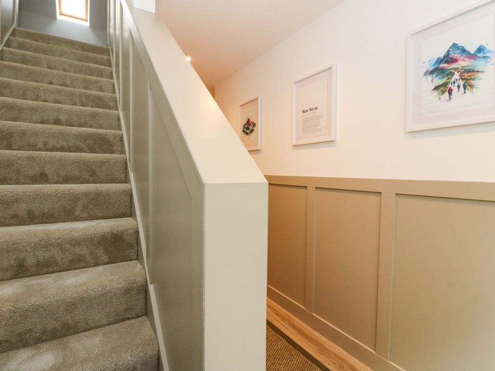 A hallway with a staircase and artwork at Nevis Bridge House in Fort William