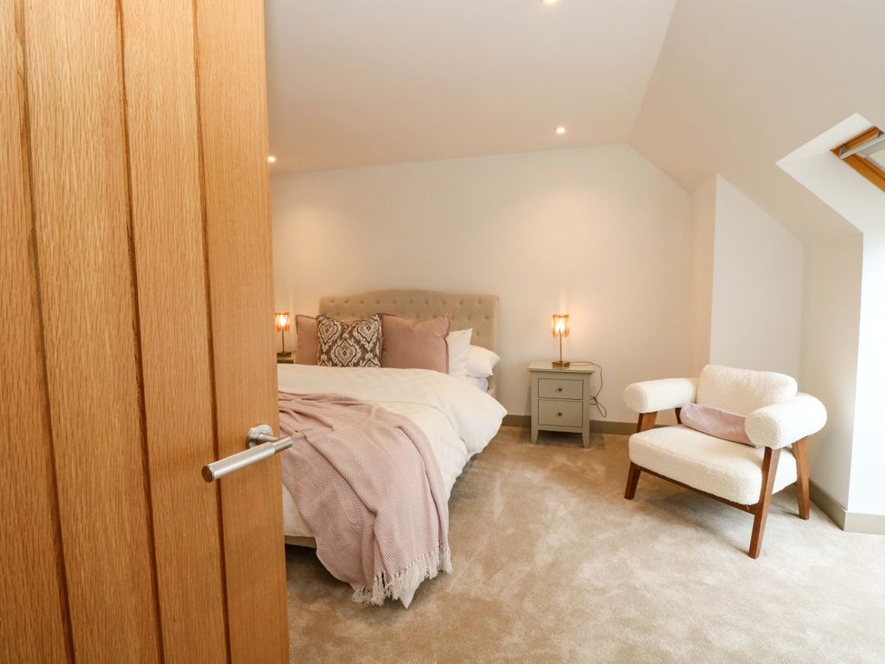 A bedroom with a bed and a chair at Nevis Bridge House in Fort William