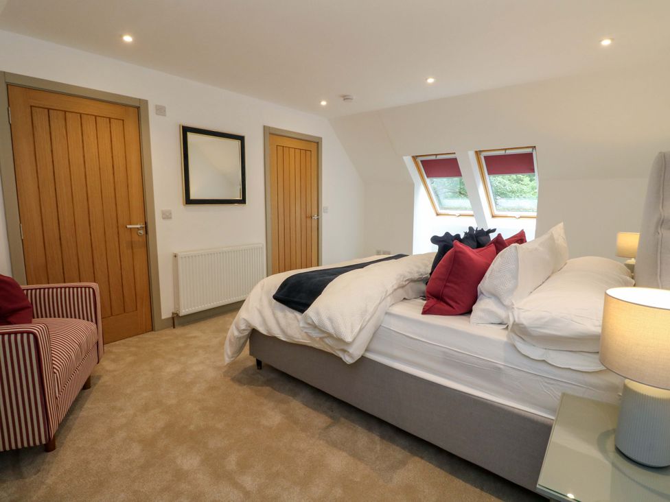 A bedroom with a bed and armchair at Nevis Bridge House in Fort William