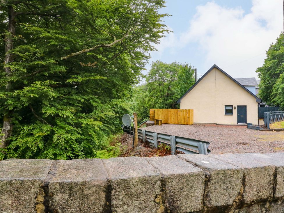 A house with a gravel area and trees around at Nevis Bridge House in Fort William