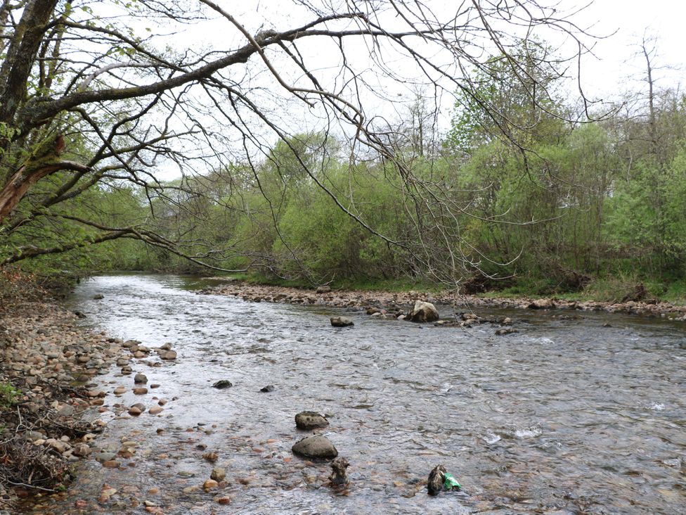 A river with rocks and trees along the bank at Nevis Bridge House in Fort William