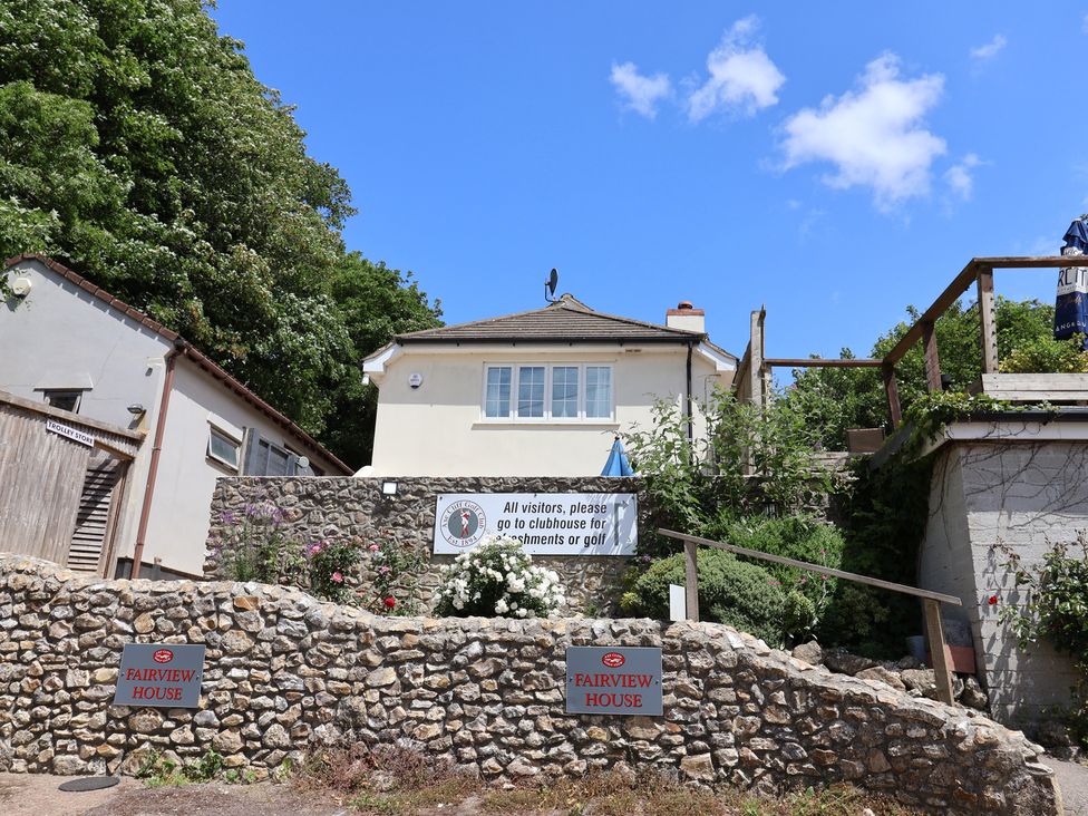 A house with a stone wall and signs at Fairview House in Axmouth