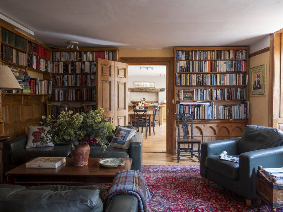 A living room with bookshelves and a coffee table at Manor Farmhouse in Dittisham
