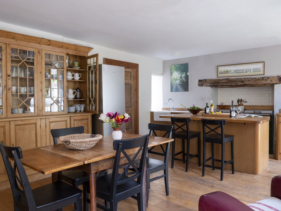 A kitchen with a dining table and cabinets at Manor Farmhouse in Dittisham