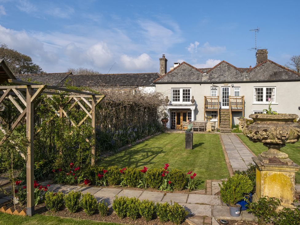 A garden view featuring a house with steps and a planter at Manor Farmhouse in Dittisham