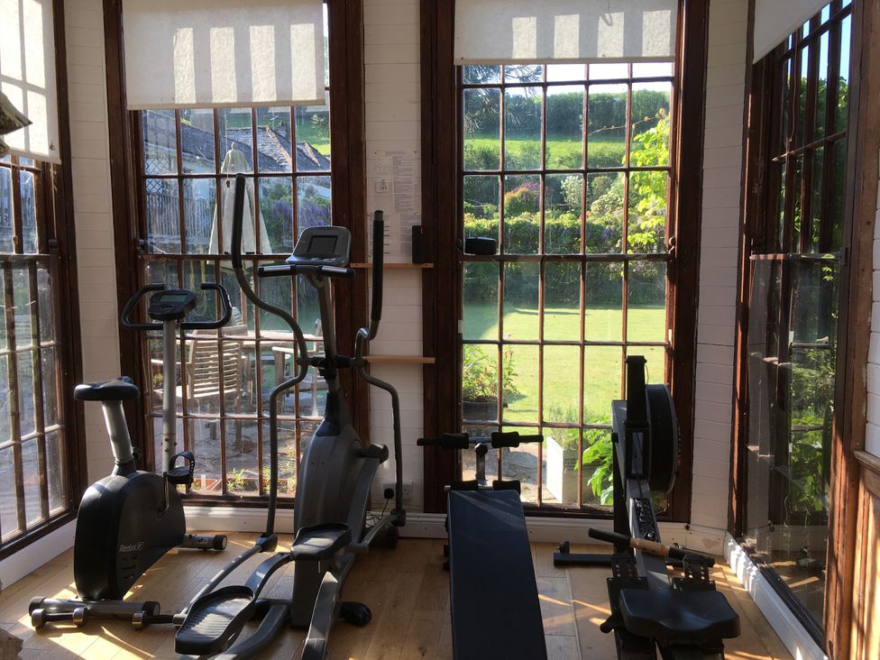 A gym with exercise equipment and large windows at Manor Farmhouse in Dittisham