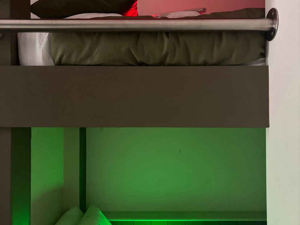 A bunk bed with a green light in the lower section at The Miners Hall Retreat in Stanley, County Durham