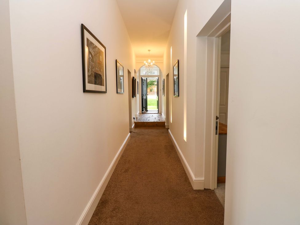 A hallway with door at the end and framed photographs on walls at The Miners Hall Retreat, Stanley, County Durham