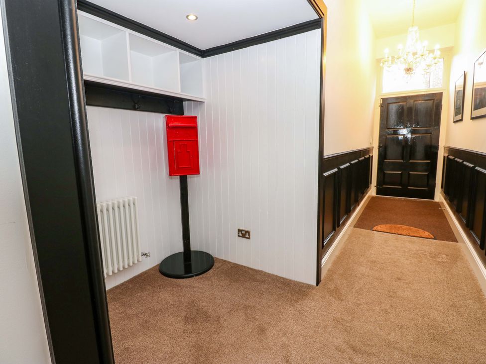 A hallway with a red post box and shelf at The Miners Hall Retreat in Stanley, County Durham