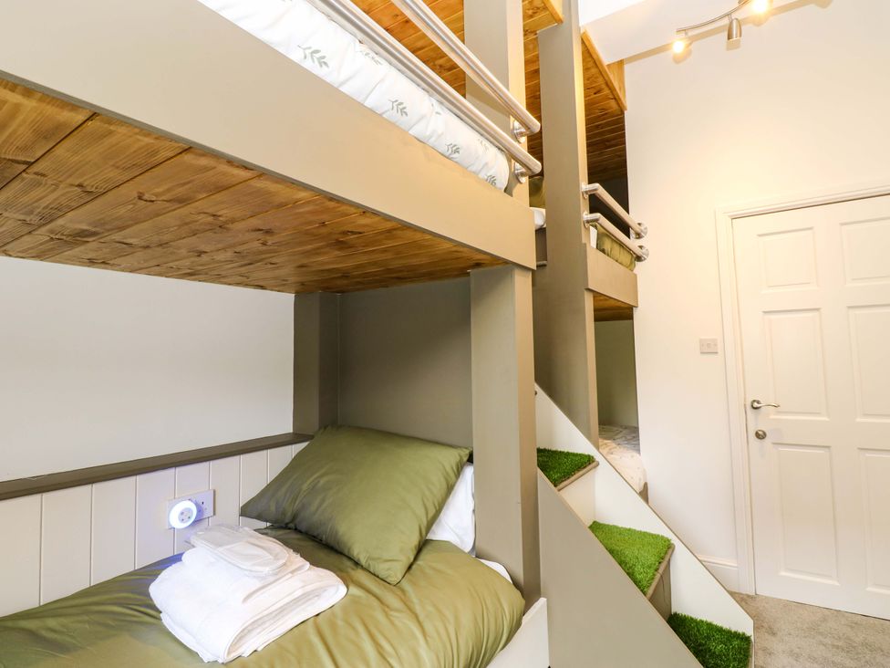 A bedroom with bunk beds and a decorative staircase at The Miners Hall Retreat in Stanley, County Durham