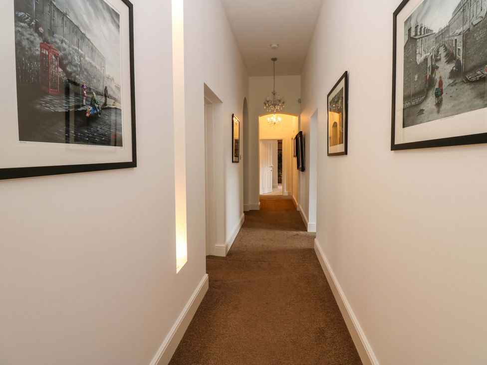 A hallway with artwork on walls and a chandelier at The Miners Hall Retreat in Stanley, County Durham
