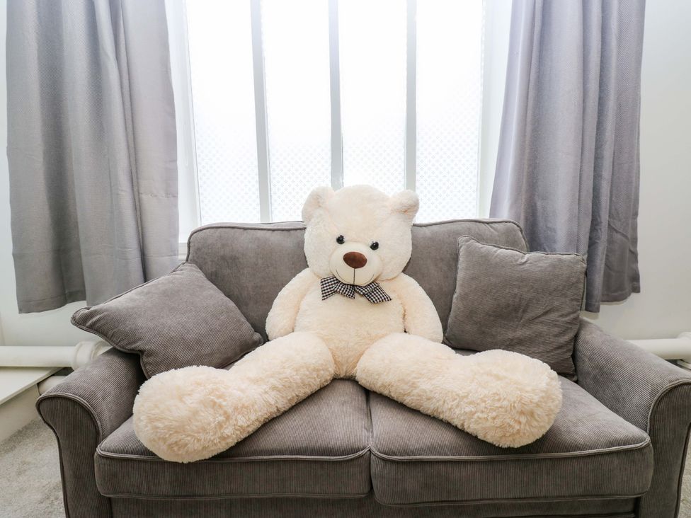 A teddy bear sitting on a couch in a living room at The Miners Hall Retreat in Stanley, County Durham
