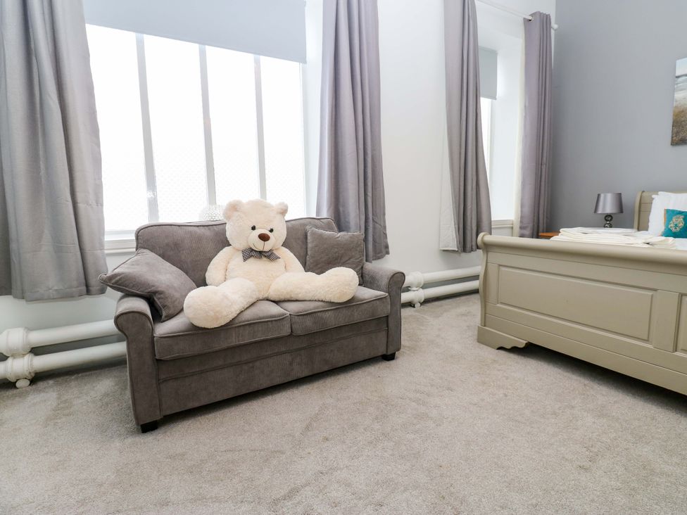 A bedroom featuring a sofa with a teddy bear and a bed at The Miners Hall Retreat in Stanley, County Durham