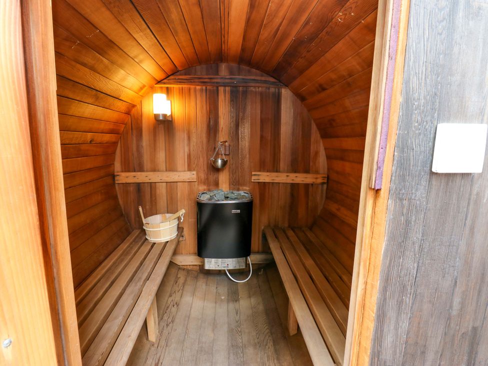 A sauna with wooden benches and a stove at The Miners Hall Retreat, Stanley, County Durham
