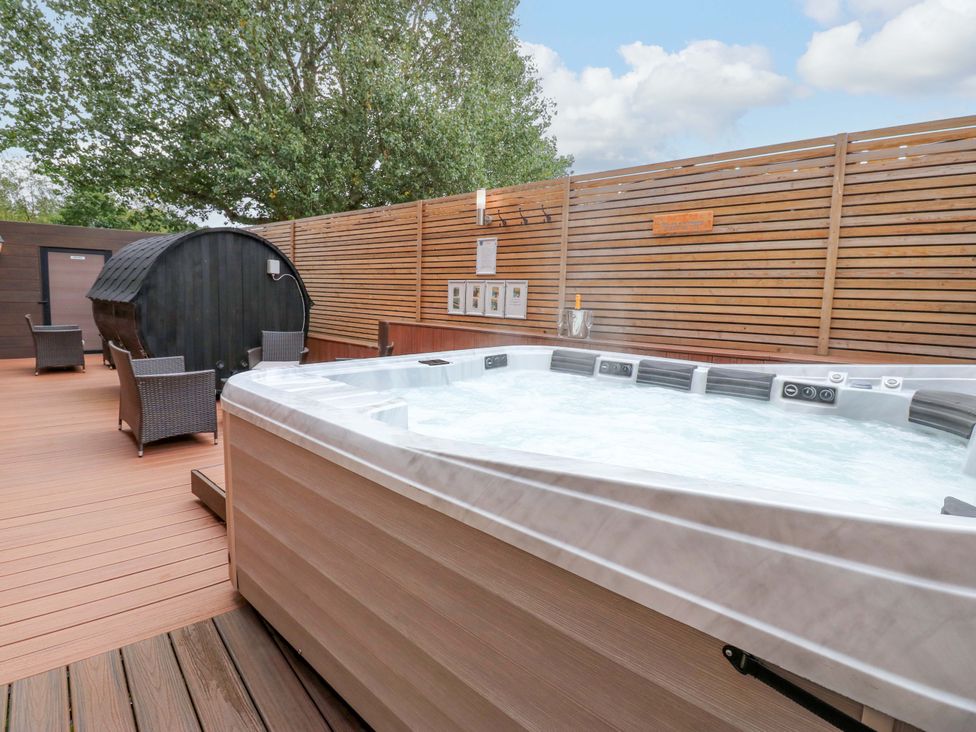 An outdoor area with a hot tub and wooden seating at The Miners Hall Retreat in Stanley, County Durham