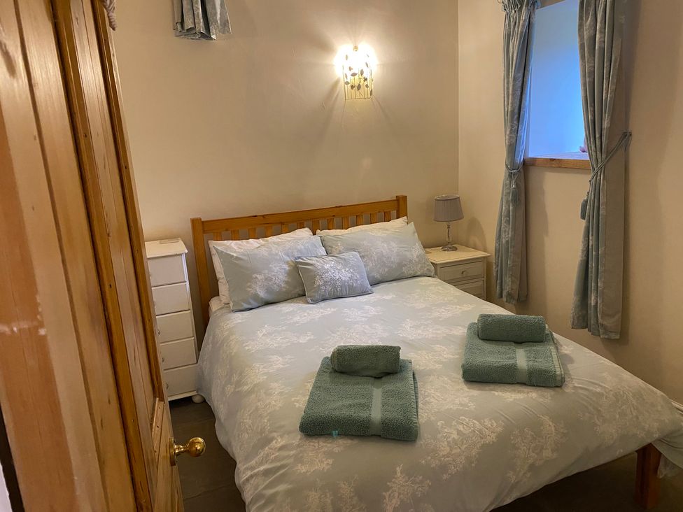 A bedroom with a bed and nightstand at Puddleduck Cottage Thornton-Le-Dale