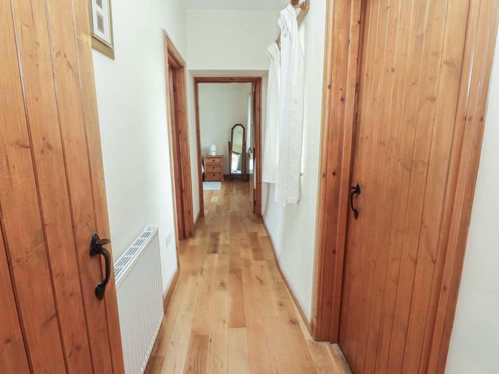 A hallway with wooden doors and a mirror at Bryn Caled in Llanarmon near Y Ffor