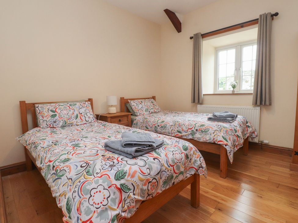 A bedroom with two beds and a window at Bryn Caled in Llanarmon near Y Ffor