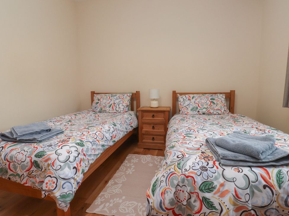 A bedroom with two single beds and a bedside table at Bryn Caled Llanarmon near Y Ffor