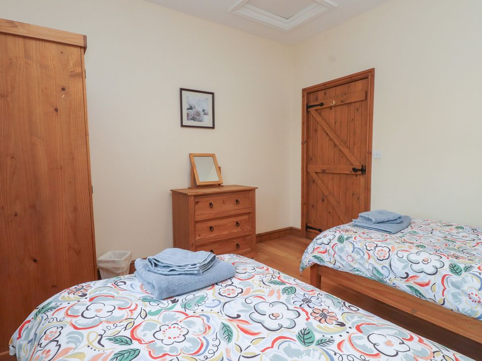 A bedroom with two beds and wooden furniture at Bryn Caled in Llanarmon near Y Ffor