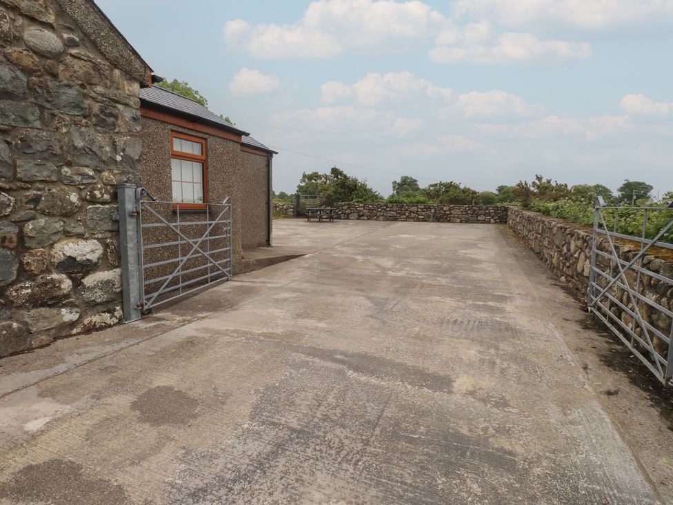 A concrete area with a gate and stone wall at Bryn Caled in Llanarmon near Y Ffor