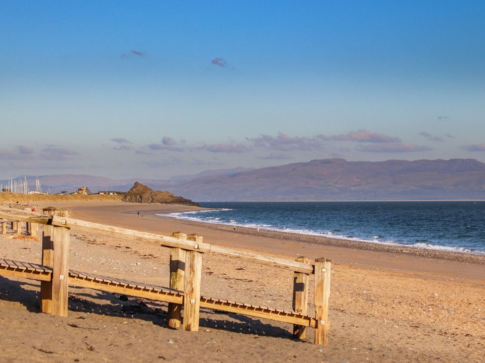 A beach with a wooden boardwalk and mountains in the background at Bryn Caled in Llanarmon near Y Ffor