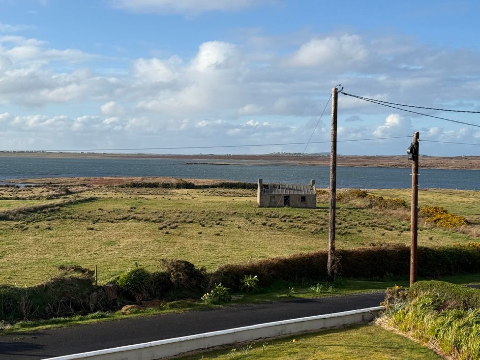 A view of a field and water with a building in the foreground at Geesala