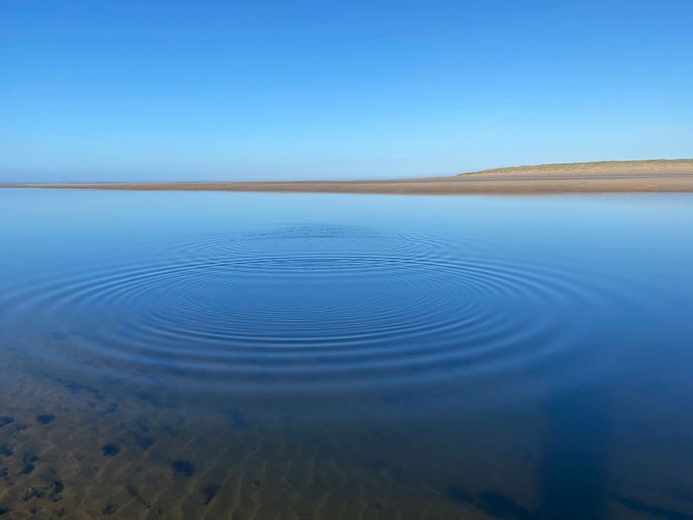 A body of water with ripples and blue sky at Geesala