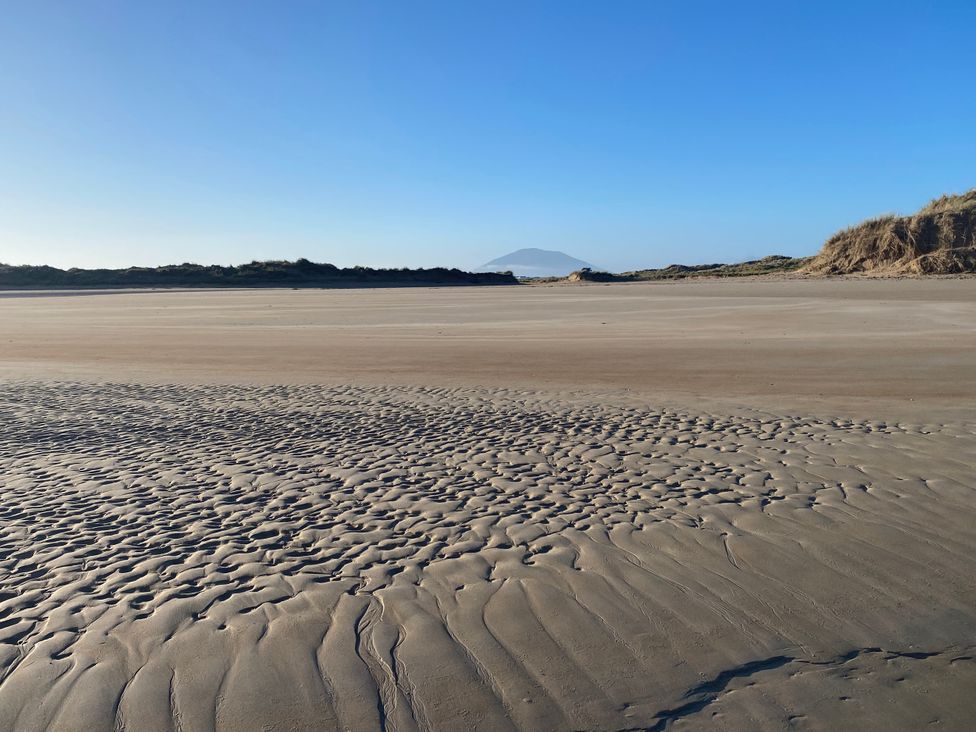 A beach with sand patterns and distant mountain at Geesala
