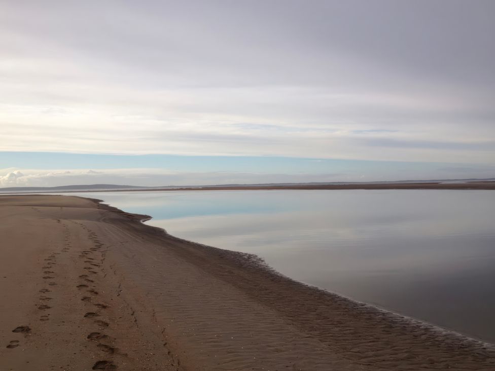 A beach with footprints leading to a calm water at Geesala in Gweesalia