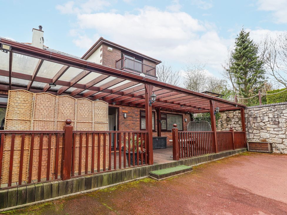 An outdoor area with a covered pergola and wooden decking at Acorns in Holywell