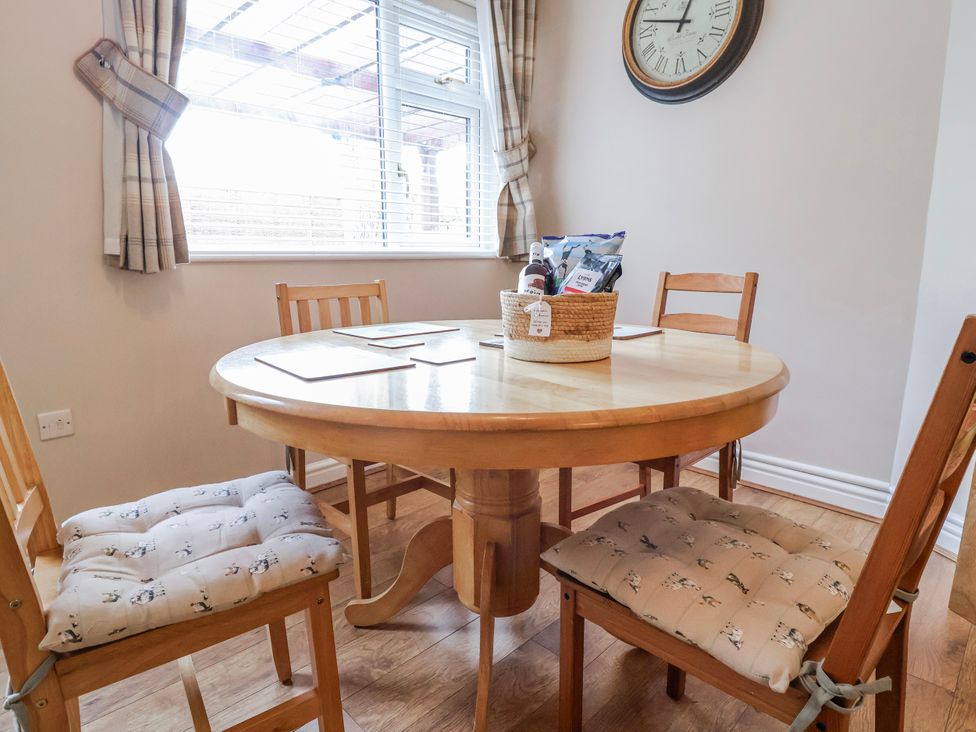 A dining room with a circular table and chairs at Acorns in Holywell
