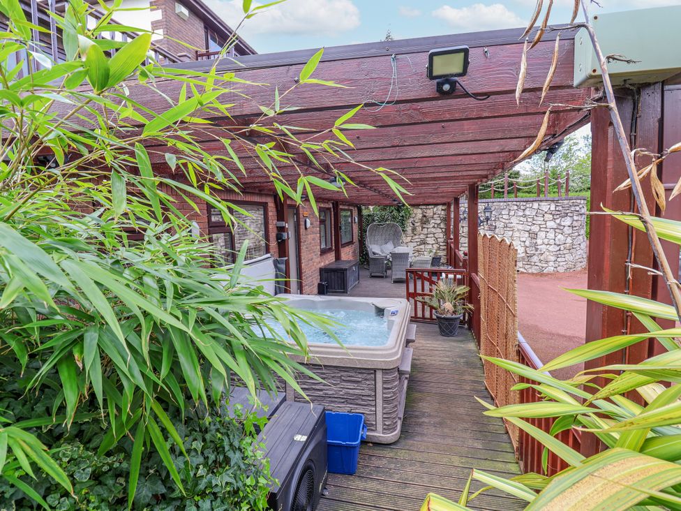 An outdoor area with a hot tub and seating at Acorns in Holywell