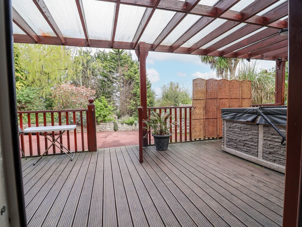 An outdoor deck with a hot tub and a table at Acorns in Holywell