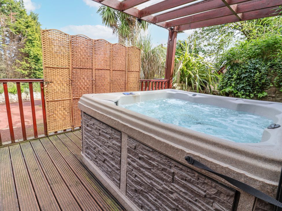 A hot tub on a wooden deck at Acorns in Holywell