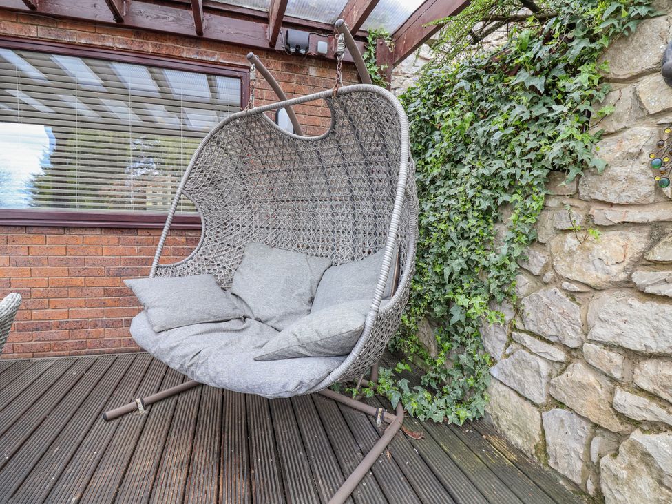 A hanging chair with cushions in an outdoor seating area at Acorns Holywell