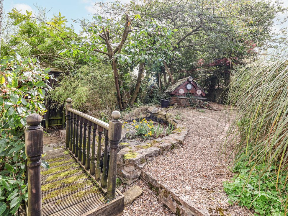 A garden path with a small pond and a house at Acorns in Holywell