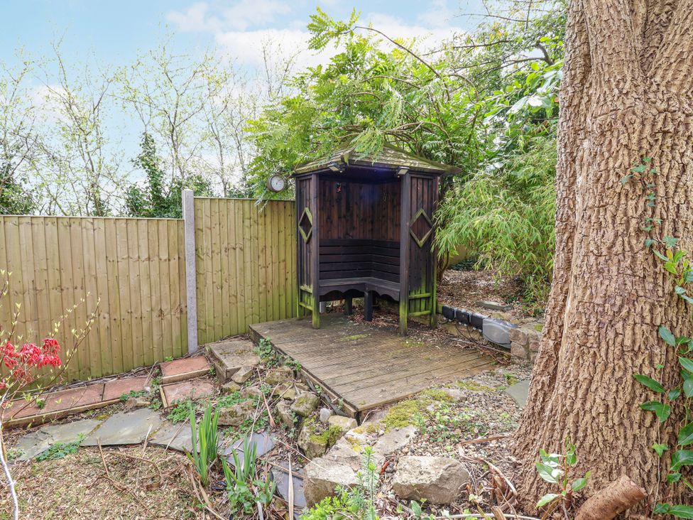 A garden with a wooden structure and plants at Acorns Holywell
